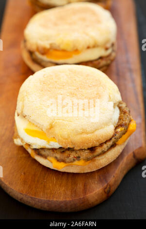 Homemade pork roll egg sandwich on a rustic wooden board on a black surface, side view. Closeup. Stock Photo