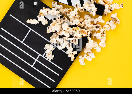 Popcorn and clapperboard on colorful background. Top view. Stock Photo