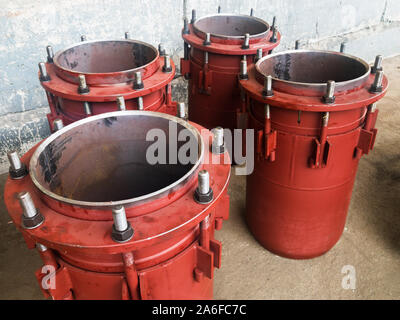 Red gland expansion joints for heating main on concrete floor. Heat and power concept. Stock Photo