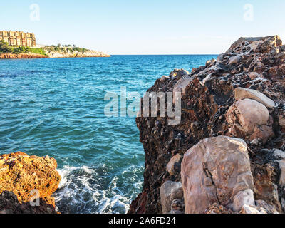 Sea waves near the Rocky coast. Blue water. Yellow rocks. Vacation travel concept. Stock Photo