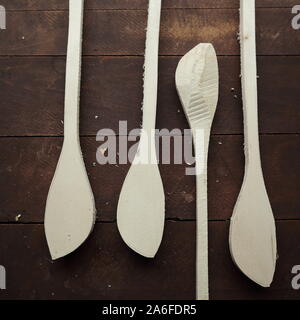 4 wooden spoon blanks rough cut for hand carving spoons on a dark wooden table with a small amount of sawdust. Stock Photo