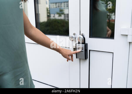 Woman Using Key Safe To Retrieve Keys From House Stock Photo