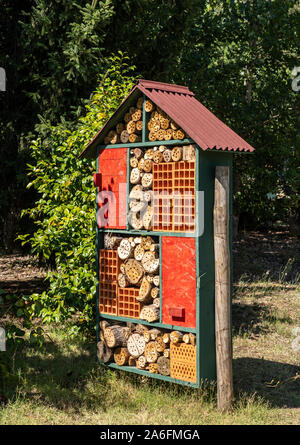 Construction for bird and insect hotel or home in garden with drilled tree trunks and branches Stock Photo