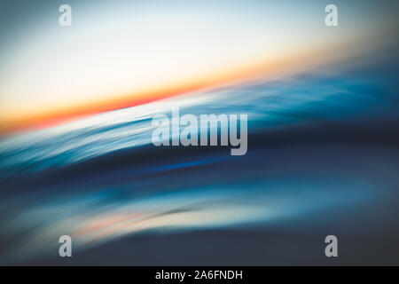 Abstract seascape with blurred panning motion. Before sunrise. Blue sea waves and sun on a horizon Stock Photo
