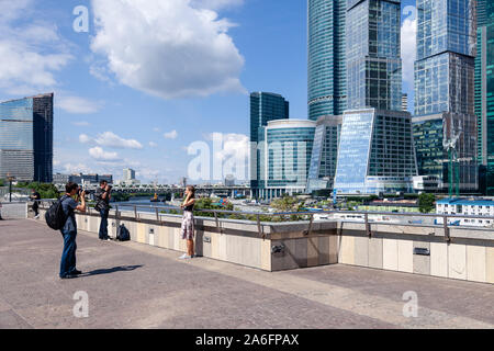 Russia Moscow 2019-06-17 Man shoot woman on photo camera on background of Moscow City skyline, International Business Center, landscape with view of t Stock Photo