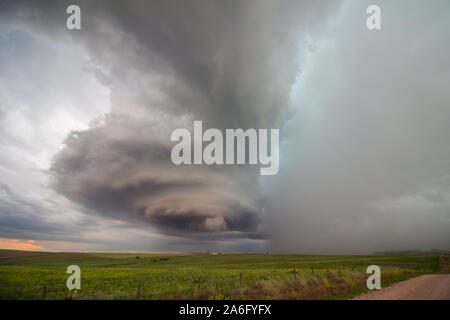 The tall, rotating updraft of a supercell thunderstorm towers over the plains in eastern Wyoming, with rain and hail falling. Stock Photo