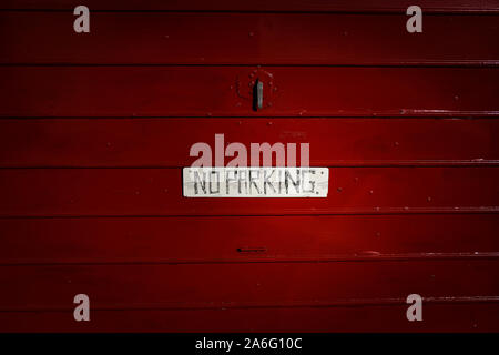 A sign saying No Parking on a red garage door in a street of terrace houses in the poor poverty area of Stoke on Trent Stock Photo