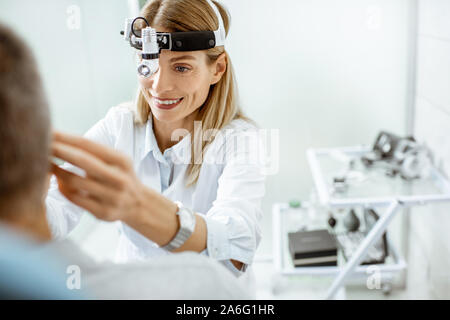 Portrait of a female confident otolaryngologist during a medical examination of a patient at the ENT office Stock Photo