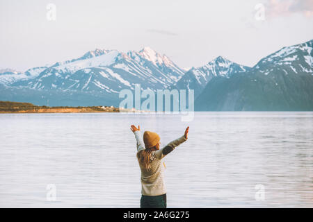 Woman tourist raised hands enjoying mountains and fjord view outdoor travel vacations in Lyngen Alps Norway Stock Photo