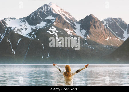Traveler woman raised hands enjoying mountains Lyngen Alps view travel adventure vacations in Norway healthy lifestyle Stock Photo