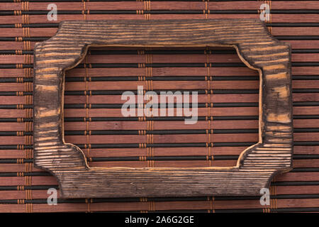 Beautiful frame, sign board cut from a solid board, lies on a bamboo mat. Close-up. Top view Stock Photo