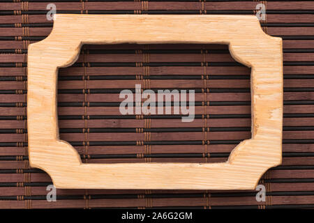 Beautiful frame, sign board cut from a solid board, lies on a bamboo mat. Close-up. Top view Stock Photo