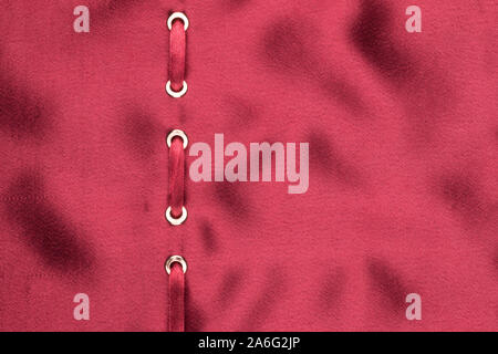 Red ribbon are inserted in a red wavy satin. Fashionable beautiful background. With space for design, text place. Top view Stock Photo