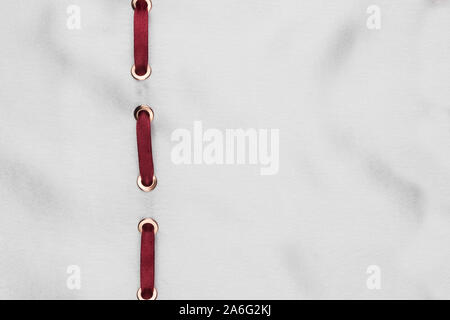 Red ribbon are inserted in a white wavy satin. Fashionable beautiful background. With space for design, text place. Top view Stock Photo