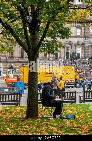 Glasgow, Scotland, UK. 25th October 2019: An artist drawing underneath a tree in George Square. Stock Photo