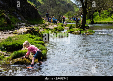 A pretty little girl paddling by the famous Dovedale stepping stones in the Derbyshire Peak District National Park Stock Photo