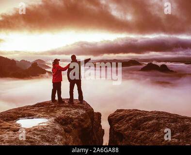 Romantic date in misty mountains. Man shows girlfriend something interesting in far distance. Stock Photo