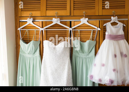 Wedding dress, and bridesmaids dresses hanging on novelty wooden coat hangers, ready for the wedding day ahead Stock Photo