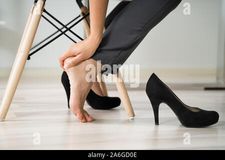 Low Section Of Young Businesswoman Rubbing Her Feet In Office Stock Photo
