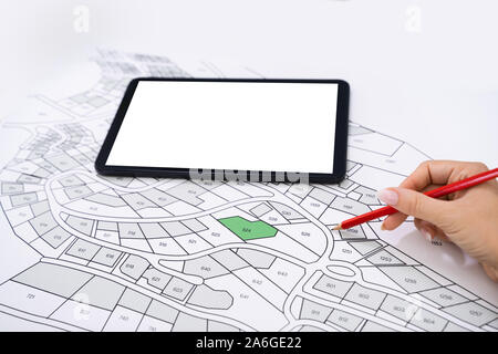 Close-up Of Human Hand Holding Pencil Over Paper Cadastre Map Stock Photo