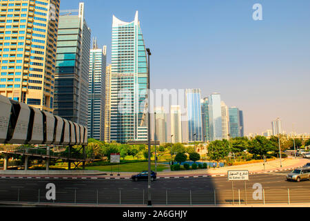 Dubai / UAE - October 15, 2019: Jumeirah Lakes Towers buildings and park. JLT road with pedestrian bridge. Stock Photo