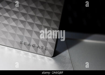 A 4tb portable Seagate HDD, hard disc drive lying on a laptop computer, storage device Stock Photo