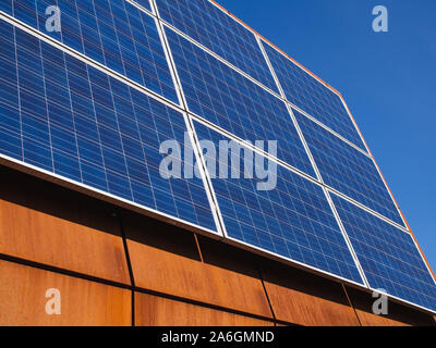 Photovoltaic solar panels on the corten steel roof of a city university building. Stock Photo