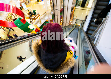 A pretty young mother with a buggy and little baby girl travelling down an escalator at the Intu Potteries Shopping centre, precinct, mall Stock Photo