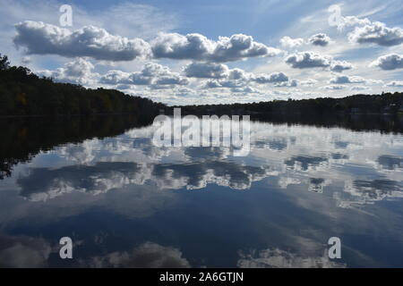 A light breeze sends ripples to the calm waters of Mystic Lake in Arlington, MA, with reflecting white cumulus clouds on the lake's waters. -02