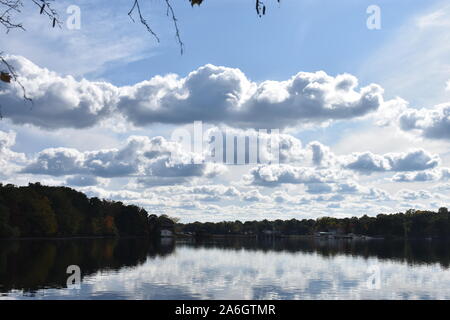 A light breeze sends ripples to the calm waters of Mystic Lake in Arlington, MA, with reflecting white cumulus clouds on the lake's waters. -08 Stock Photo