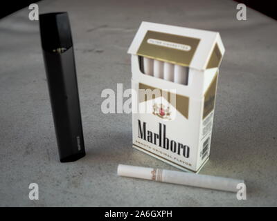 smok infinix vape pod electronic cigarette device with a pack of marlboro  cigarettes and one cigarette placed outside on a white textured table,  isola Stock Photo