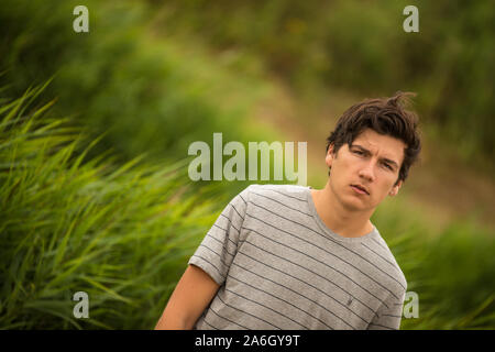 A young tall dark haired model poses for pictures in an old abandoned industrial compound Stock Photo