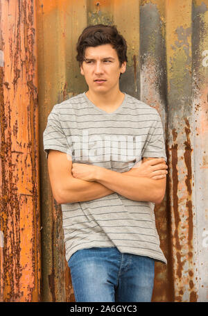 A young tall dark haired model poses for pictures in an old abandoned industrial compound Stock Photo