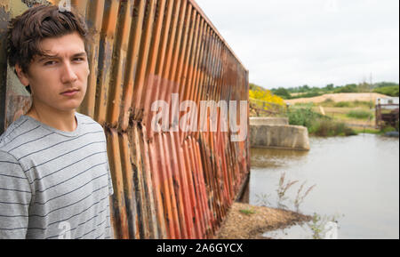A young tall dark haired model poses for pictures in an old abandoned industrial compound Stock Photo