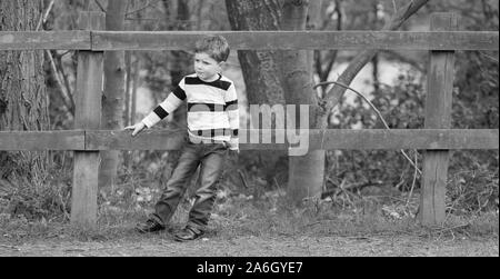 A handsome little boy leaning on a fence on a family walk at Colchester Country Park Stock Photo