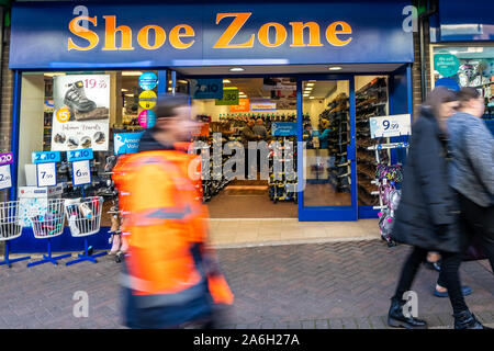 People walk past the discount shoe shop 