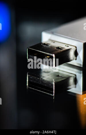 USB memory stick, bluetooth connection adapter on a mirrored background with studio lighting, close up Stock Photo