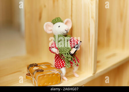 Handmade mohair stuffed toy. felt rat with a bottle of wine in his hands and a yellow suitcase next. Stock Photo