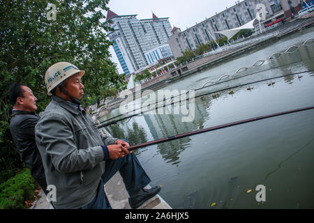 One Asian Chinese man fishing in pond in city. Stock Photo