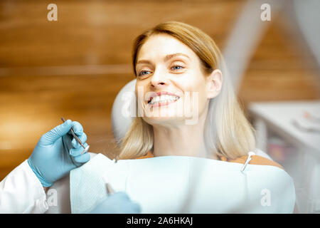 Portrait of a beautiful and cheerful woman sitting as a patient on the dental chair during a medical examination at the dental office Stock Photo