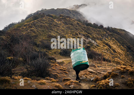 Nepal Porter Sherpa carrying big tank for water in the Himalayas Mountains, Annapurna trekking, Nepal Stock Photo