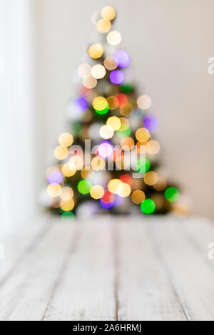 Merry Christmas! White candlestick flashlight stands on the background beautiful blurred christmas tree with luminous garland. Selective focus. Stock Photo