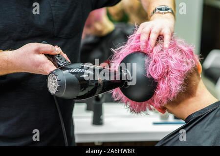 Hands Of Hairdresser Checks Short Pink Hair Of Girl On Gray