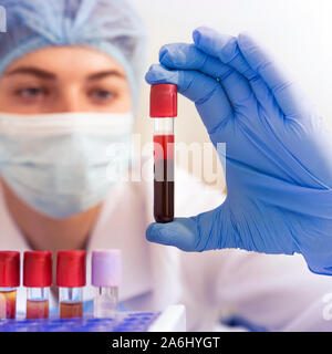 Woman lab worker holding test tube doing blood analysis Stock Photo