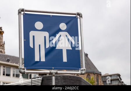 WC toilets sign. Mobile toilets signage in the city for an outdoors event, cloudy sky background. Square metal frame and blue fabric with human silhou