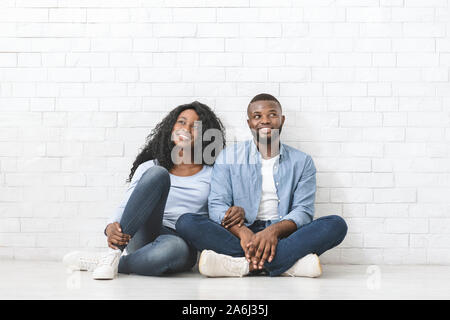 Dreamy black couple sitting on floor, planning interior Stock Photo