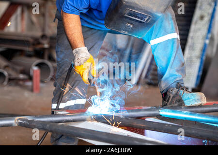 Metal worker is welding metals with protection of him self. Stock Photo
