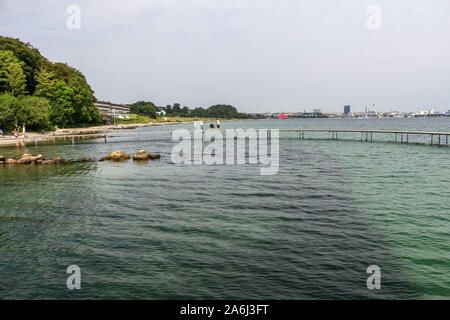 People walking by the The Infinite Bridge (Den Uendelige Bro) - circle shaped wooden pier built on a sea coast of a Aarhus Bay on a Varna Beach/Ballehage Beach, created by architect Niels Povlsgaard and Johan Gjødes are seen in Aarhus, Denmark on 30 July 2019 © Michal Fludra / Alamy Live News