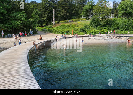 People walking by the The Infinite Bridge (Den Uendelige Bro) - circle shaped wooden pier built on a sea coast of a Aarhus Bay on a Varna Beach/Ballehage Beach, created by architect Niels Povlsgaard and Johan Gjødes are seen in Aarhus, Denmark on 30 July 2019 © Michal Fludra / Alamy Live News