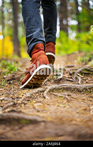 A man in red leather boots walks in the amazing autumn forest. Footwear close up with copy spase. Travel concept. Stock Photo